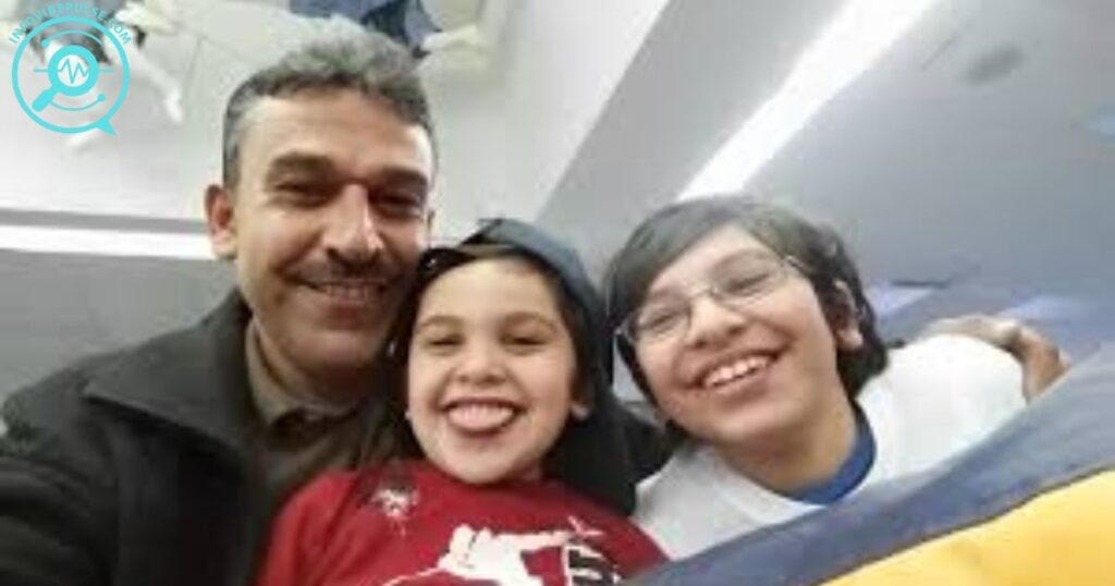 A smiling man with two children taking a selfie indoors, all appearing joyful and happy together.